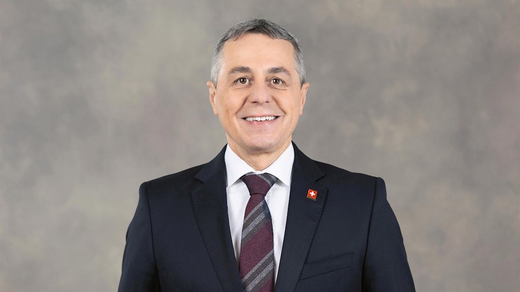 Bundesrat Ignazio Cassis steht im Anzug vor einem grauen Hintergrund.