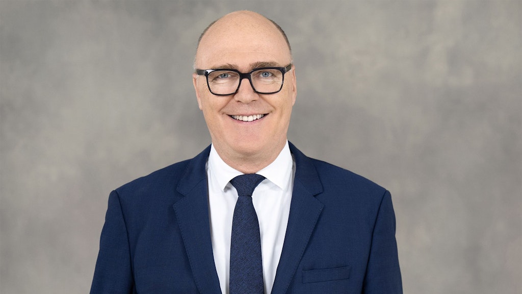 Federal Councillor Martin Pfister stands in front of a grey background wearing a suit.