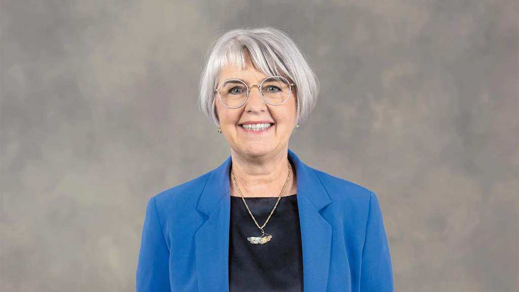 La consigliera federale Elisabeth Baume Schneider indossa una giacca blu e posa davanti a uno sfondo grigio.