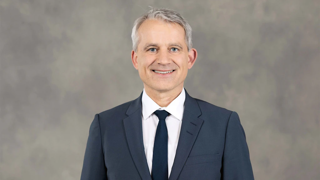 Il consigliere federale Beat Jans in giacca e cravatta davanti a uno sfondo grigio